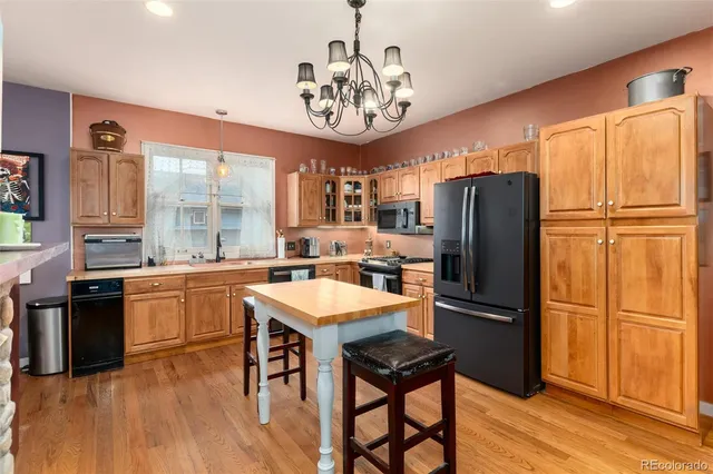 a kitchen with stainless steel appliances granite countertop a refrigerator a sink dishwasher a stove a refrigerator and a dining table with wooden floor