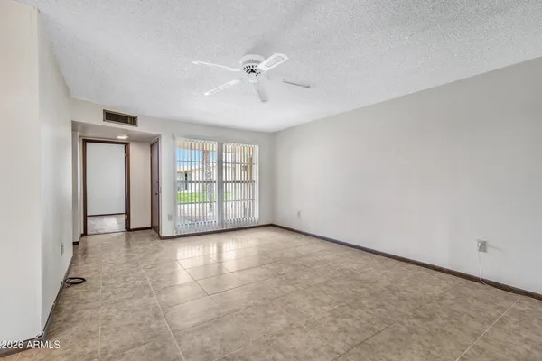 an empty room with chandelier fan and windows
