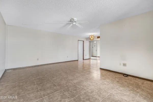 wooden floor in an empty room with a chandelier fan