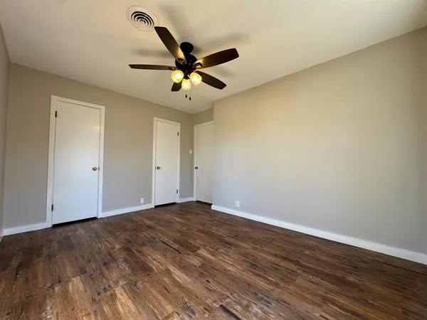 a view of a big room with wooden floor and windows