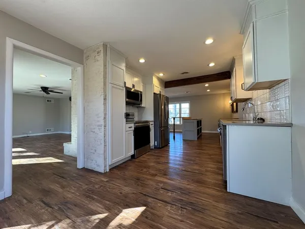 a view of kitchen with kitchen island wooden floor and refrigerator