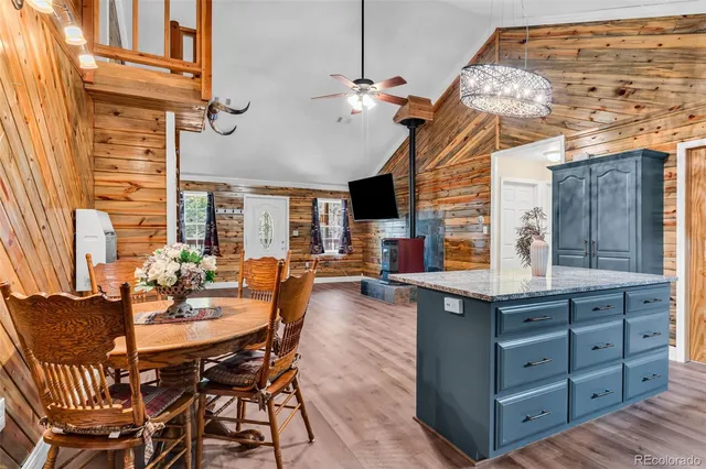 a dining hall with stainless steel appliances kitchen island granite countertop a table chairs and a wooden floor