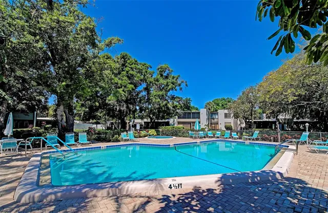 a view of a swimming pool with a bench and trees around