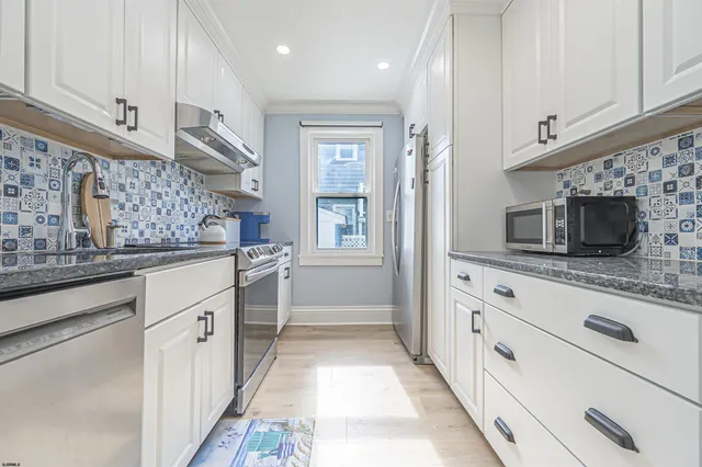 a kitchen with stainless steel appliances kitchen island granite countertop a refrigerator and a stove top oven