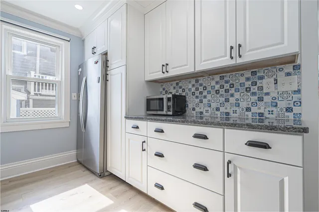 a kitchen with white cabinets and window