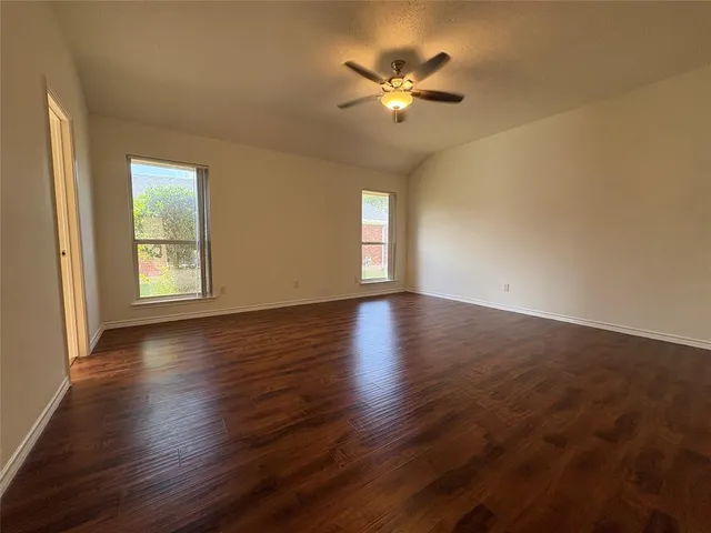 a view of an empty room with a window and wooden floor
