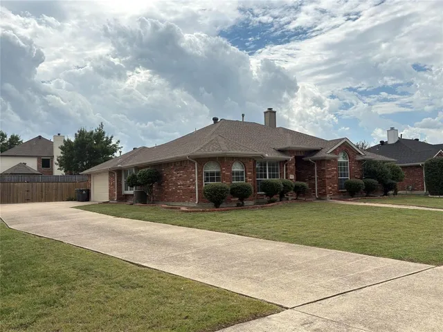 a front view of a house with a garden and trees