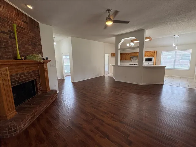 an empty room with wooden floor a fireplace and windows
