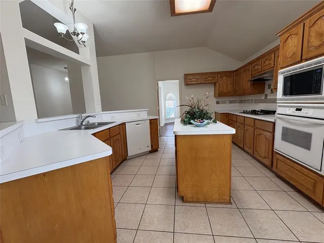 a kitchen with stainless steel appliances granite countertop a sink counter space cabinets and a stove top oven