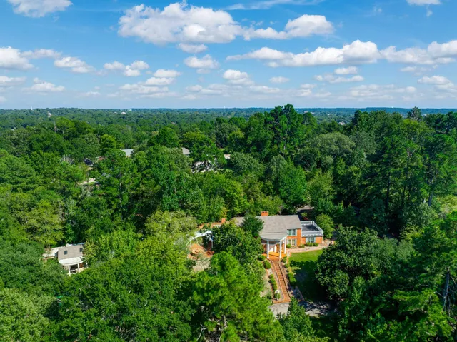 an aerial view of residential house with outdoor space and trees all around