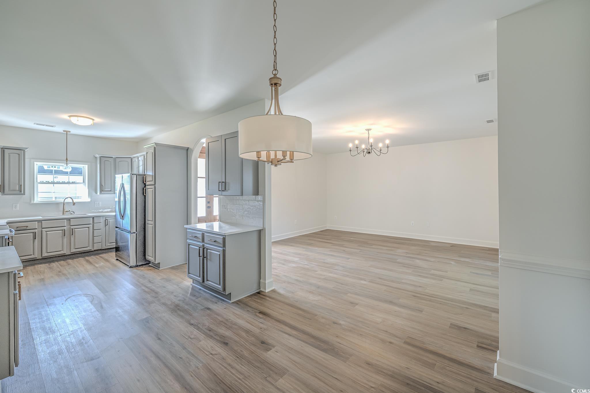 4000 Bayfield Loop Murrells Inlet, SC 29576 - Photo 11 of 33 Kitchen with gray cabinets, freestanding refrigerator, a chandelier, tasteful backsplash, and light countertops