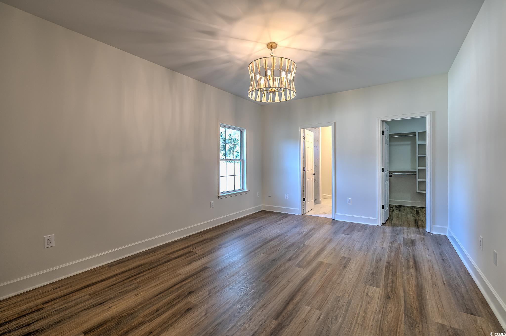 4000 Bayfield Loop Murrells Inlet, SC 29576 - Photo 13 of 33 Unfurnished bedroom with a chandelier, dark wood-style floors, and a spacious closet
