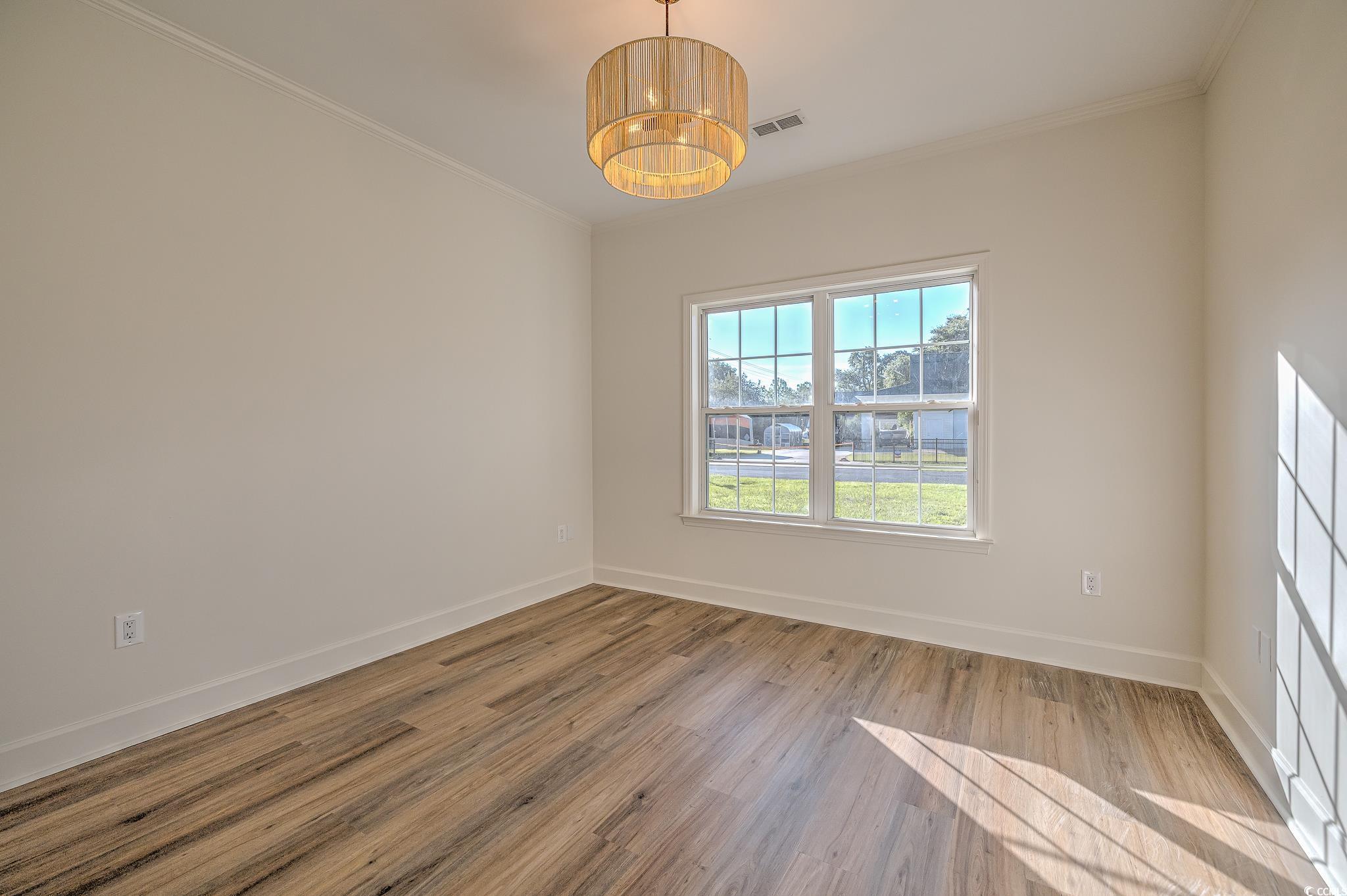 4000 Bayfield Loop Murrells Inlet, SC 29576 - Photo 20 of 33 Empty room featuring wood finished floors, ornamental molding, and a chandelier