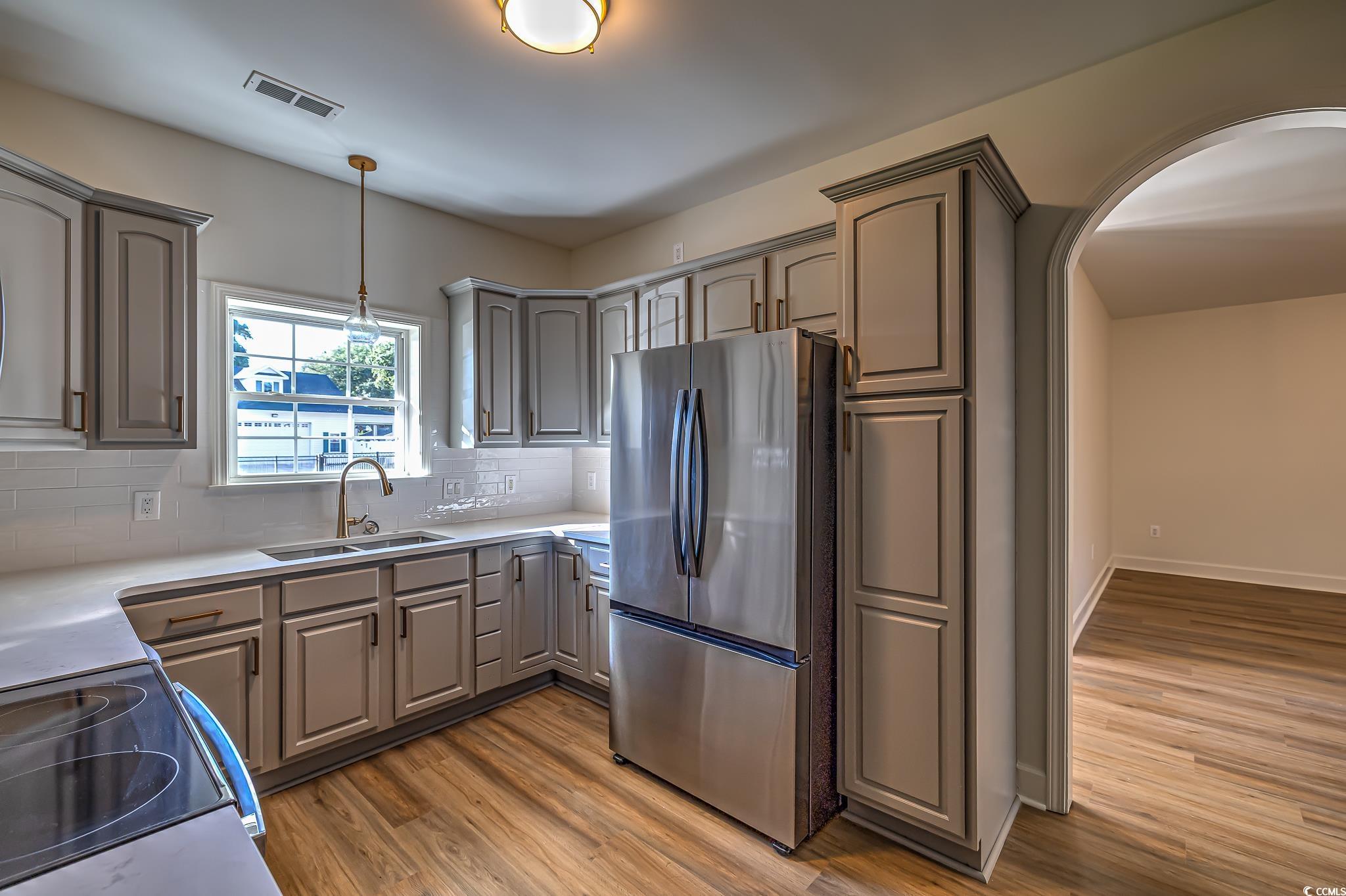 4000 Bayfield Loop Murrells Inlet, SC 29576 - Photo 27 of 33 Kitchen with freestanding refrigerator, gray cabinetry, wood finished floors, tasteful backsplash, and arched walkways