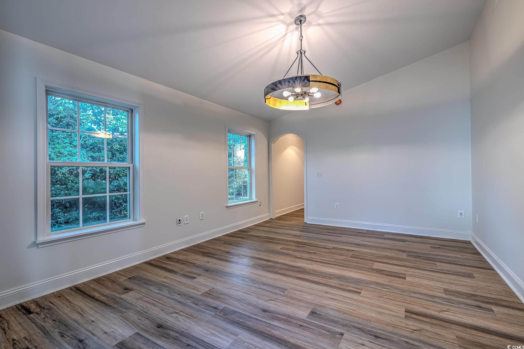 4000 Bayfield Loop Murrells Inlet, SC 29576 - Photo 32 of 33 Spare room with a chandelier, arched walkways, and dark wood-style flooring