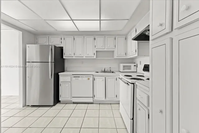 a kitchen with white cabinets a refrigerator and a stove