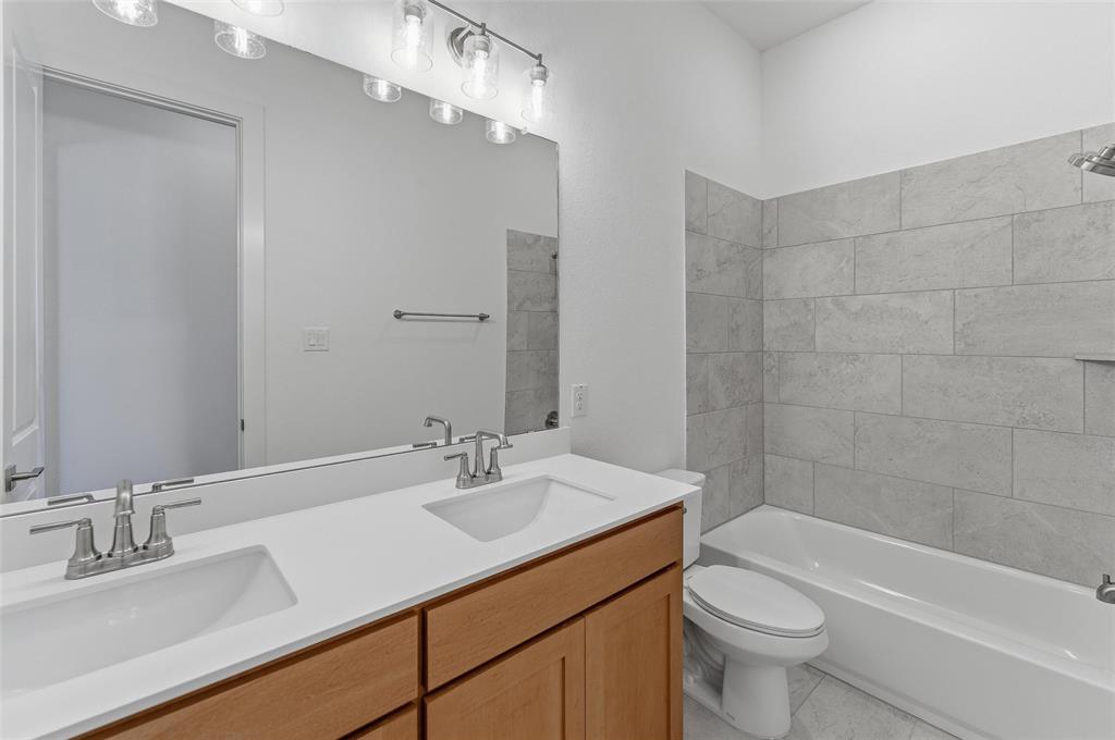 815 Vly Rdg Road Van Alstyne, TX 75495 - Photo 17 of 29 Bathroom featuring a double vanity with light wood-finish cabinetry, white countertop, and integrated sinks
