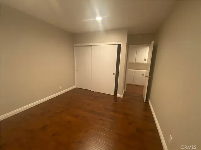 an empty room with wooden floor and mirror