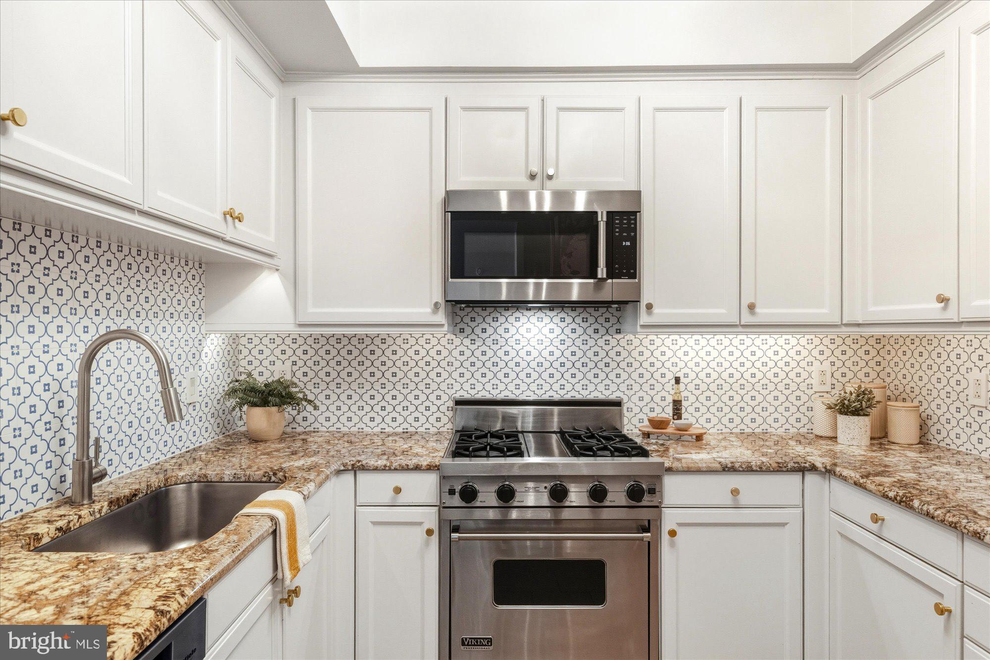1155 23rd Street Northwest, Unit 8H Washington, DC 20037 - Photo 5 of 22 a kitchen with granite countertop a stove a sink and a microwave