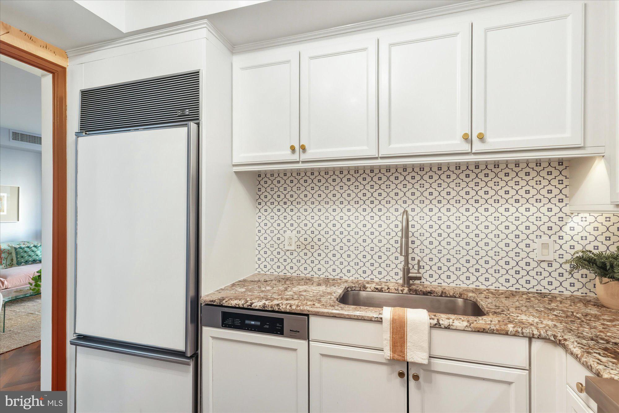 1155 23rd Street Northwest, Unit 8H Washington, DC 20037 - Photo 6 of 22 a kitchen with granite countertop cabinets and white appliances