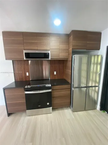 a view of kitchen with refrigerator and wooden floor