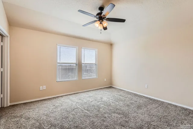 an empty room with a window and a fan