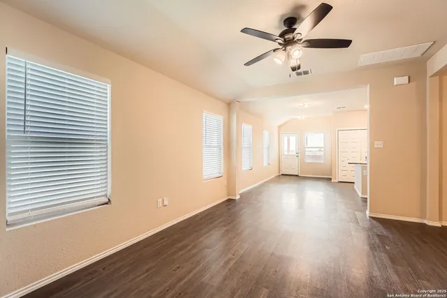 a view of an empty room with a window and wooden floor