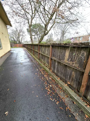a view of a backyard with wooden fence and large trees