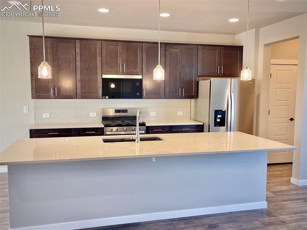 3527 Summer Dream Avenue Colorado Springs, CO 80922 - Photo 3 of 26 a large kitchen with stainless steel appliances a large counter top a stove and a refrigerator