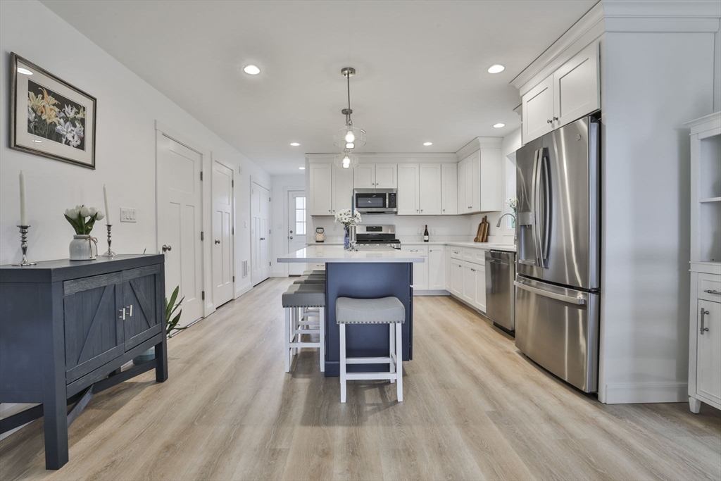 207 Beach Road, Unit C2 Salisbury, MA 01952 - Photo 4 of 35 a kitchen with stainless steel appliances granite countertop a refrigerator oven a stove a sink a dining table and chairs with wooden floor