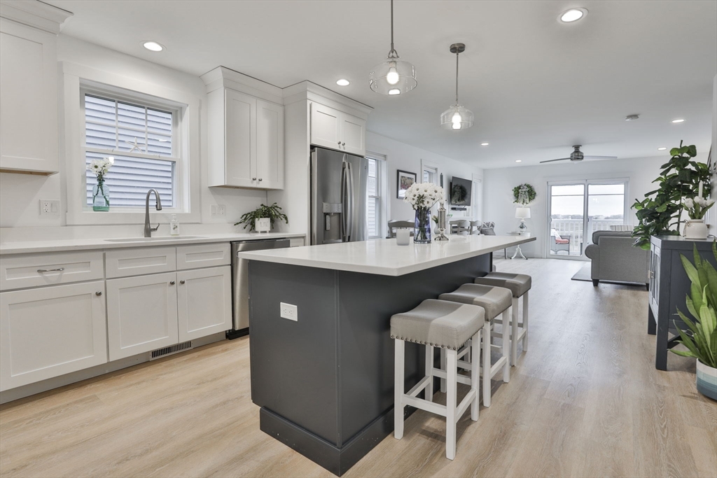 207 Beach Road, Unit C2 Salisbury, MA 01952 - Photo 7 of 35 a large kitchen with kitchen island a dining table chairs and a wooden floor