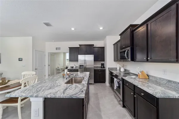 a kitchen with stainless steel appliances granite countertop sink stove refrigerator and cabinets