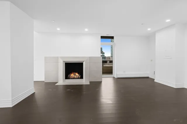 a view of an empty room with wooden floor and stairs