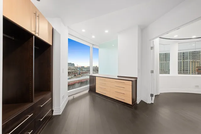 a view of an empty room with wooden floor and windows