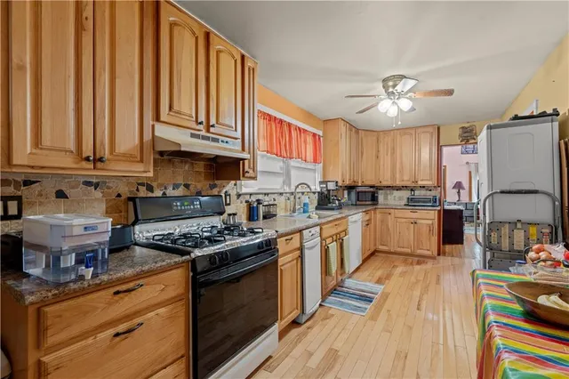 a kitchen with stainless steel appliances granite countertop a stove a sink dishwasher and cabinets with wooden floor