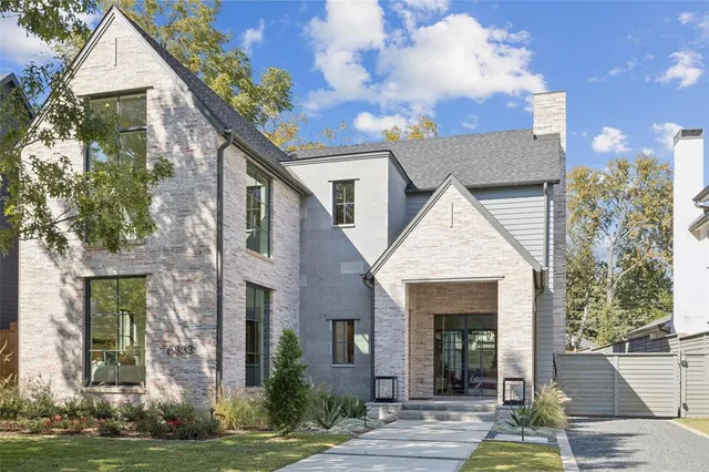 a view of a white house with potted plants and a lawn chairs