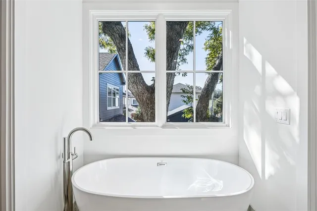 a white bath tub sitting in a bathroom next to a window