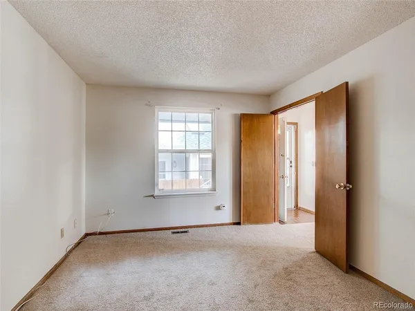 an empty room with a chandelier fan and windows
