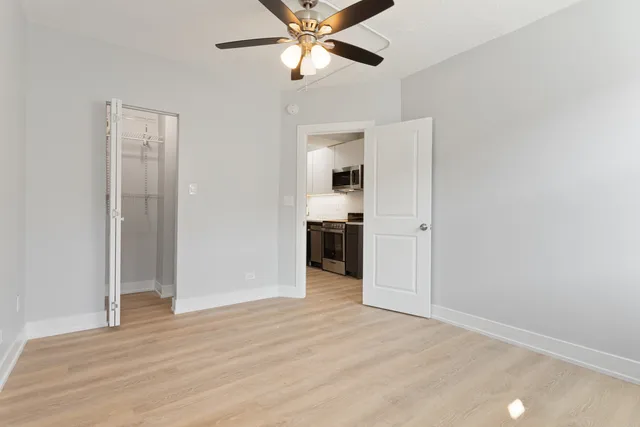 an empty room with wooden floor closet and ceiling fan