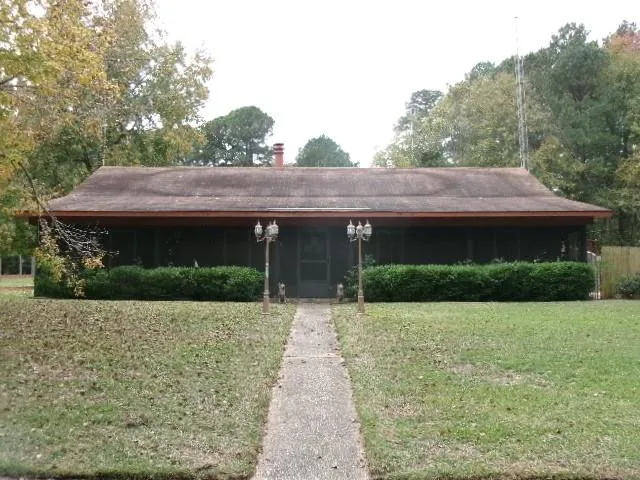 a front view of house with yard and trees in the background