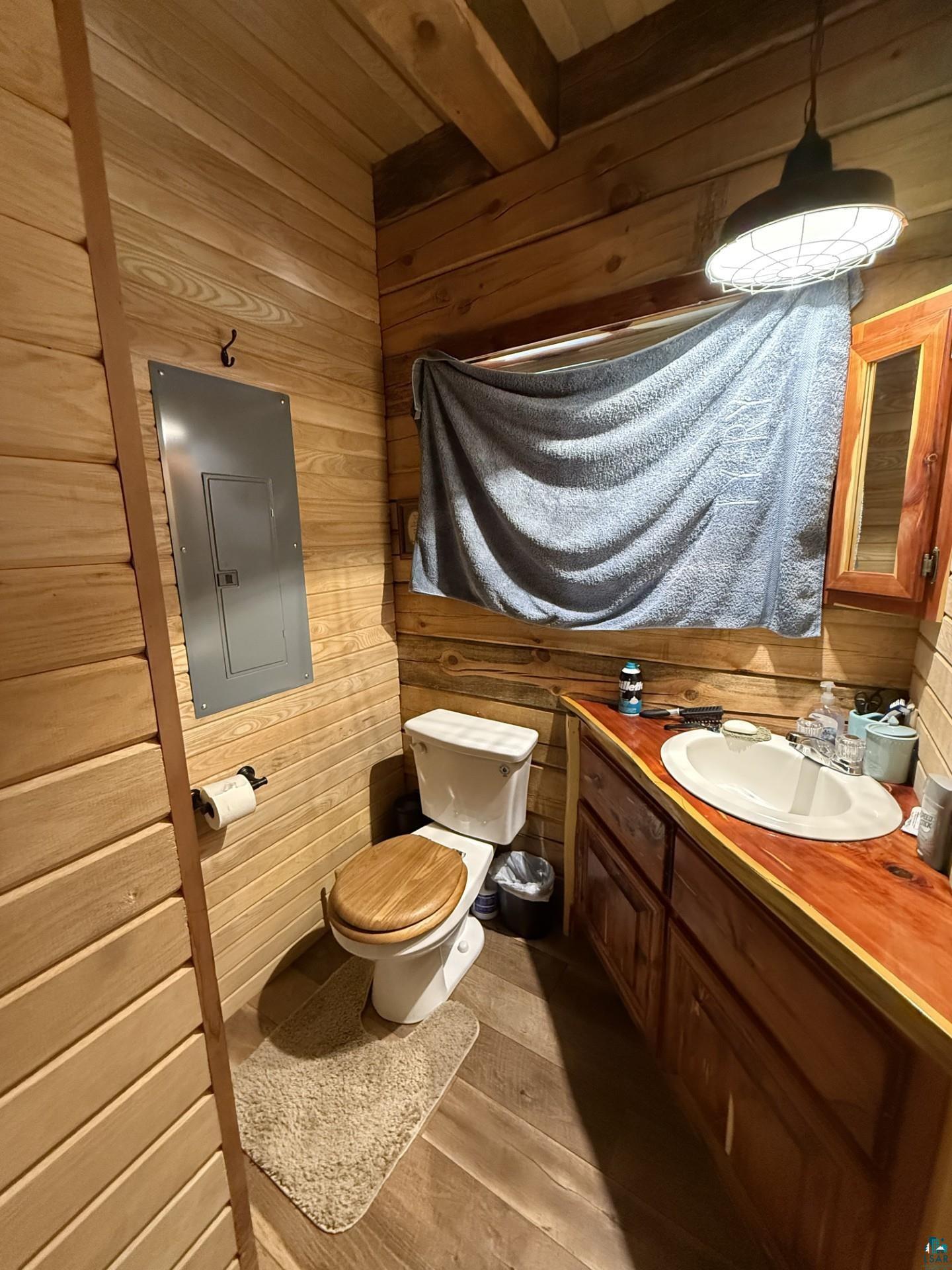 66795 Janecek Road Ashland, WI 54806 - Photo 6 of 10 Half bathroom with electric panel, wood walls, vanity, wood finished floors, and beamed ceiling