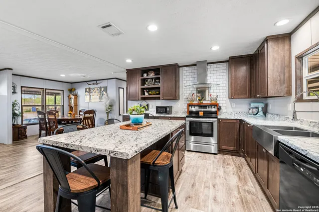 a kitchen with stainless steel appliances kitchen island granite countertop a refrigerator and a stove top oven