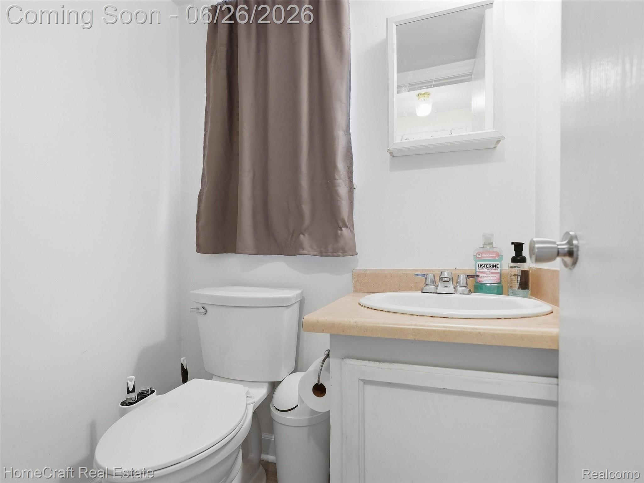 41462 Simcoe Drive Canton, MI 48188 - Photo 6 of 10 Compact bathroom featuring a white toilet, white vanity with an integrated sink, and a framed wall-mounted mirror
