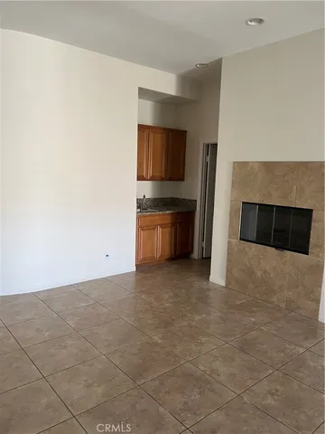 a view of kitchen and empty room with fireplace