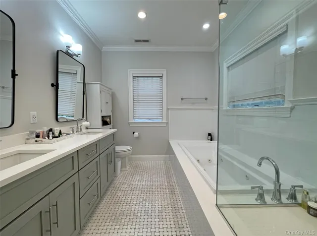 a bathroom with a tub sink double vanity granite tub shower and a mirror