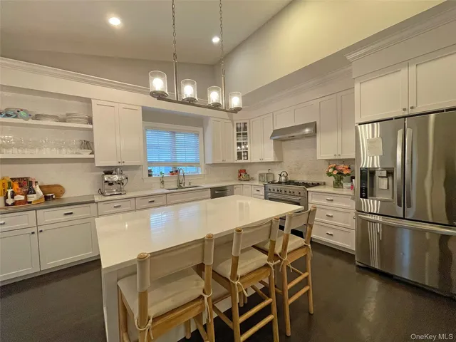 a large kitchen with kitchen island a stove a sink a refrigerator and a dining table with wooden floor