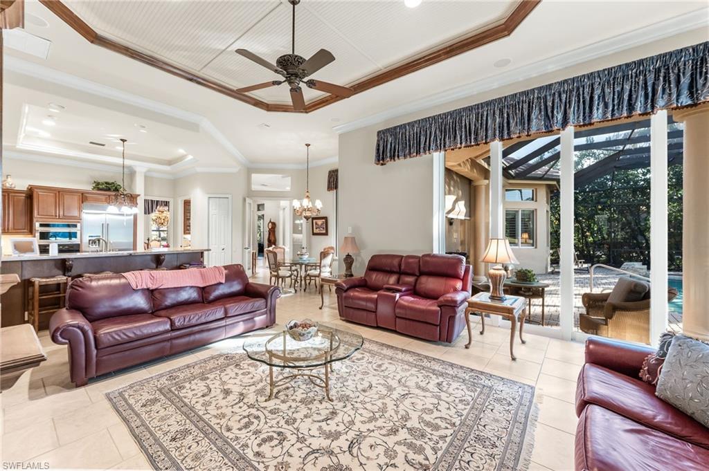 7615 Palmer Court Naples, FL 34113 - Photo 17 of 50 Living room featuring ceiling fan, a tray ceiling, ornamental molding, and suspended lighting