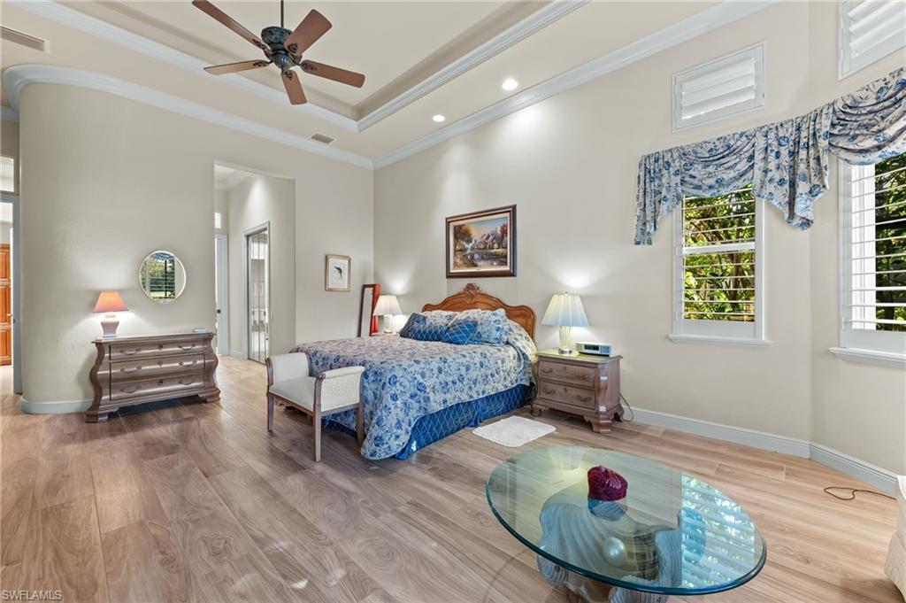 7615 Palmer Court Naples, FL 34113 - Photo 22 of 50 Bedroom featuring wood finished floors, crown molding, a ceiling fan, and a raised ceiling
