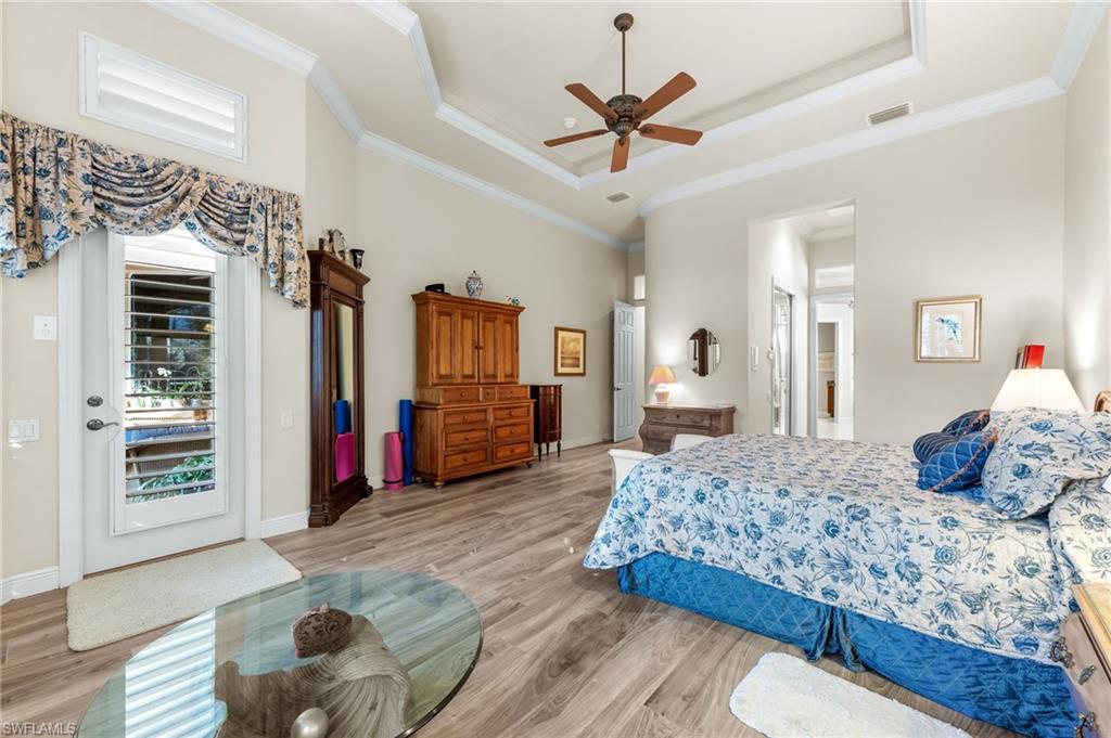 7615 Palmer Court Naples, FL 34113 - Photo 23 of 50 Bedroom with wood finished floors, a ceiling fan, a tray ceiling, and crown molding
