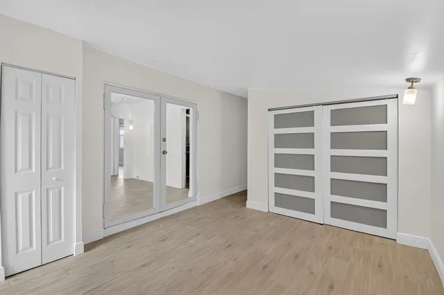 a view of an empty room with wooden floor and closet area